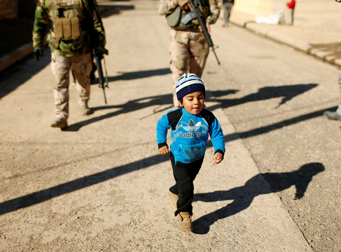 A child walks in front of Iraqi army during an operation against Islamic State militants in the neighbourhood of Intisar, eastern Mosul, Iraq, December 6, 2016. REUTERS/Ahmed Jadallah